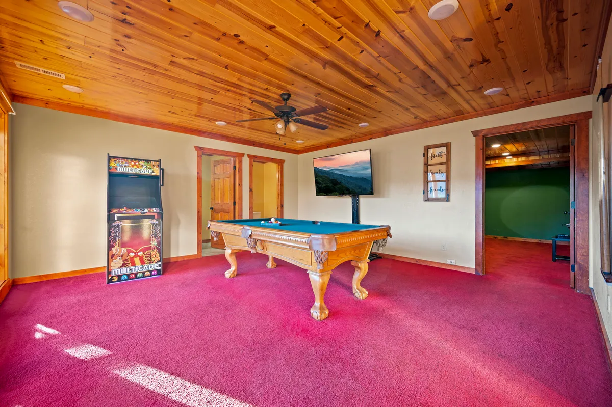 A lively game room showcasing a pool table, classic arcade machine, and television. The atmosphere is playful and energetic, hinting at friendly competition and shared entertainment among friends or family.