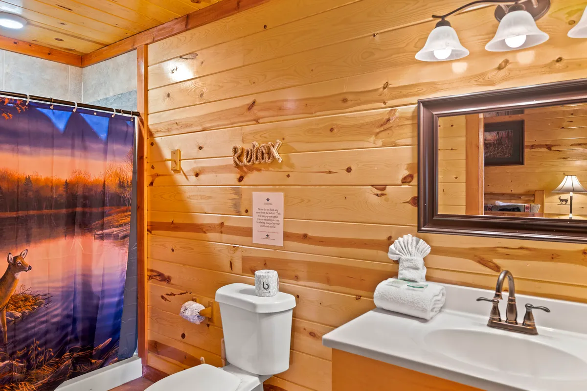 A tranquil bathroom scene with a shower curtain featuring a nature motif, neatly arranged towels, a bright sink area, and wooden wall textures. The soft lighting and thoughtful amenities evoke a sense of relaxation and self-care.